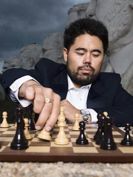 Hikaru Nakamura gra w szachy na tle figur prezydentów USA w Williamsburgu.