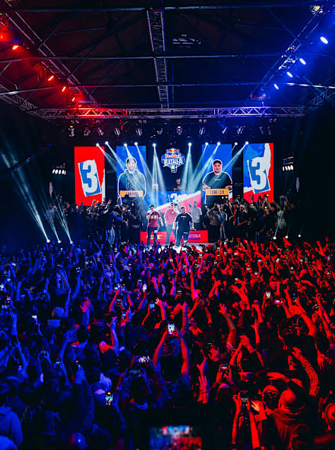 Spectators fill the venue with energy at Red Bull Batalla 2025 in Buenos Aires, Argentina, on July 26, 2025, as competitors face off on stage under vibrant red and blue lights