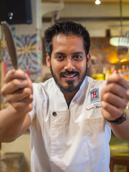 Chef Thomas Zacharias poses for a profile photo in The Bombay Canteen with a knife and fork in hand