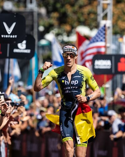 Triathlet Sebastian Kienle läuft beim Ironman Hawaii 2022 als Sechster über die Ziellinie und ballt die Faust.