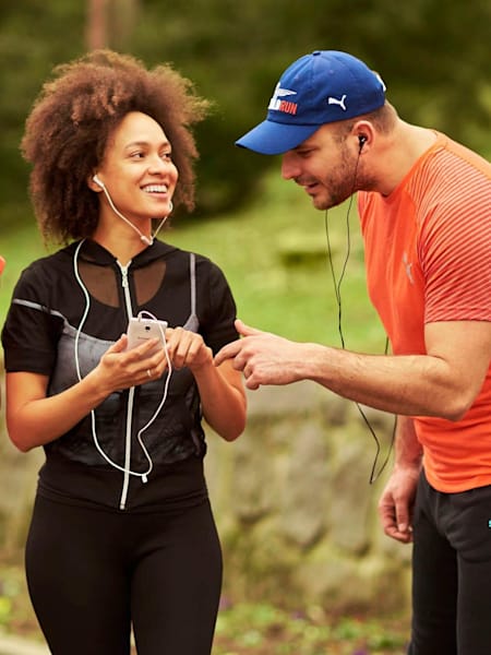 Three runners look at one of their phones while outdoors