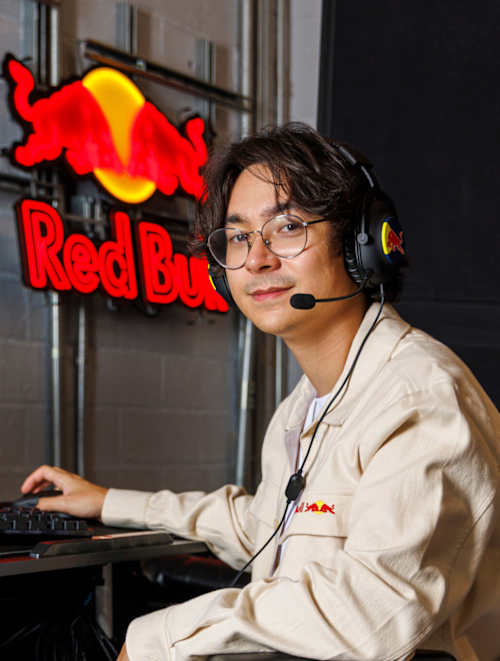 Tyson « TenZ » Ngo joue à son bureau au siège de Red Bull à Santa Monica, en Californie, le 11 juin 2025, avec un casque Red Bull et une enseigne lumineuse de la marque en arrière-plan.