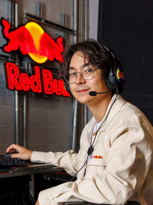 Tyson « TenZ » Ngo joue à son bureau au siège de Red Bull à Santa Monica, en Californie, le 11 juin 2025, avec un casque Red Bull et une enseigne lumineuse de la marque en arrière-plan.