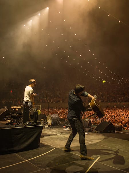 Mumford and Sons usan sus guitarras como raquetas de tenis en un concierto en Queens, Nueva York, EEUU.