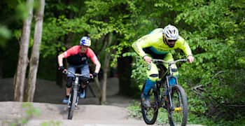 Rob Warner and Tom Oehler demonstrate their MTB pumping techniques on a trail.