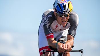 An image of triathlete Braden Currie in Red Bull helmet riding a bike in competition.