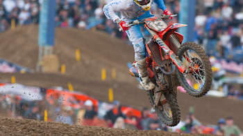 A motocross rider takes a jump out on a course.