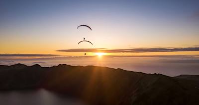 Paraglider Jean-Baptiste Chandelier at playing with a fellow pilot at sunset.