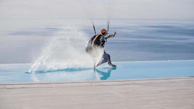 Paraglider Jean-Baptiste Chandelier skims the surface of a swimming pool during a flight.