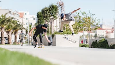 Un skateur filme un autre rider réalisant une figure en skateboard.