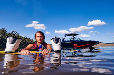 Cory Teunissen poses with his wakeboard and boat in the water