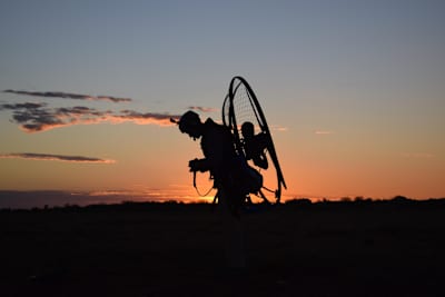 Silueta de uno de los gemelos Turner con su paramotor al atardecer en Australia.