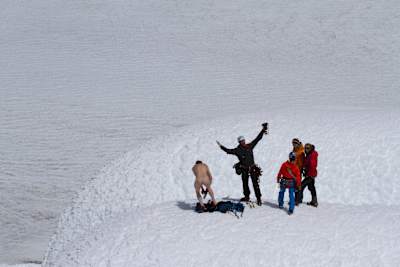 A naked man on the top of a mountain summit during the climb of Cerro Torre.