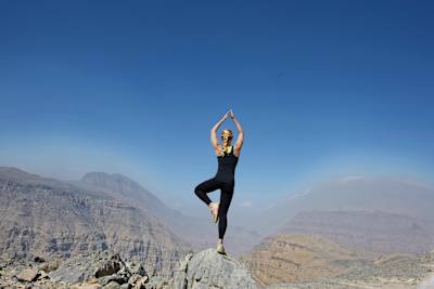 Cassie de Pecol on a mountain in Oman a yoga pose.