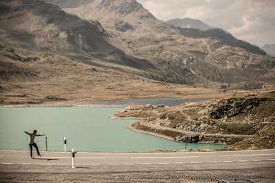 Skater performs a manual on a highway with a lack and mountains in the background.