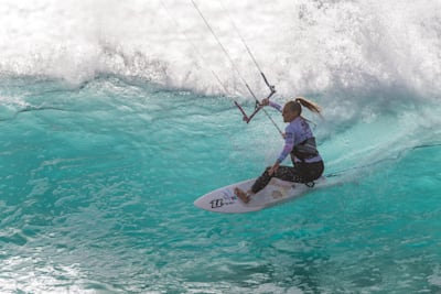 Irina Jenni fährt beim kitesurfen über eine Welle.