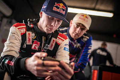 Kalle Rovanperä patrzy na swojego smartfona w przerwie między wyścigami na zawodach Drift Masters w Irlandii, 8 maja 2022, Mondello Park