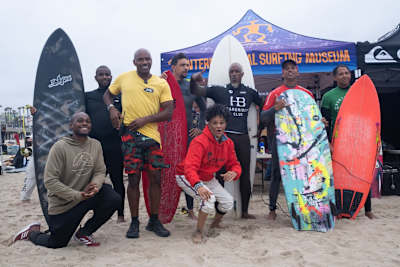 Legends and competitors, including the first Black Female professional surfer Sharon Schaffer, center, and Nathan Fluellen, creator of Great Day in the Stoke, Ryan Harris, owner of Ry Harris Shapes.