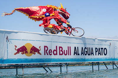 Odvážny pretekár v dračom kostýme jazdí na bicykli z okraja na Red Bull Al Agua Pato 2025, ktorý sa konal v Parque de la Familia v Santiagu v Čile.