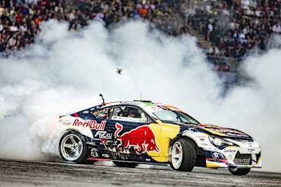 Конор Шанахан проїжджає на своєму дрифт-автомобілі в кольорах Red Bull крізь хмару диму від шин під час гранд-фіналу Red Bull Drift Masters 2025 року у Варшаві