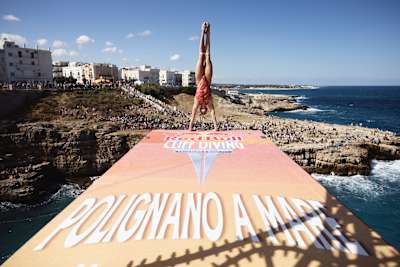 Ginni van Katwijk of the Netherlands prepares an armstand dive from the 22-metre platform during the 2026 Red Bull Cliff Diving World Series in Polignano a Mare, Italy