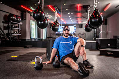 Luka Djukic poses at a modern gym in Tivat, Montenegro, on 21 May 2026, surrounded by kettlebells and hanging punch bags.