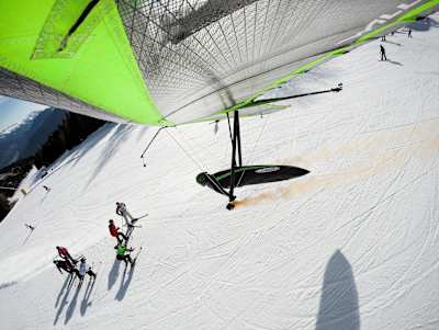 Wolgang Siess performing a speedrun over a ski slope with his hang glider