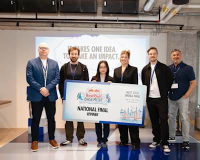 Joi Lam Chow poses with judges holding the Red Bull Basement National Final Winner board on stage at Red Bull Canada HQ in Toronto, Ontario.
