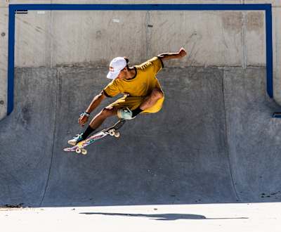 Deskorolkowiec w żółtej koszulce podskakuje na deskorolce.
