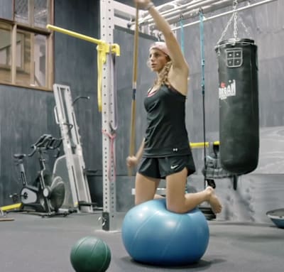 Kneel on the ball and practice full range of movement with the stick.