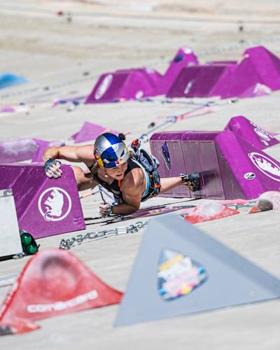 In 2024, Jessica Pilz climbs a vibrant purple climbing wall at the 2024 Red Bull Dual Ascent event in Verzasca, Switzerland