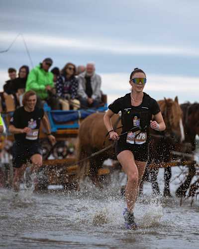 Teilnehmende kämpfen sich durch's Watt, während sich andere durch kutschieren lassen. 