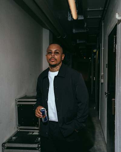 Am 29. April 2026 posiert Luciano hinter der Bühne in Köln zwischen den Instrumentenkoffern mit einer Red-Bull-Dose für Red Bull Setlist