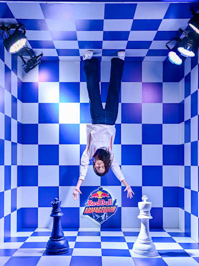 Une participante en suspension inversée dans un décor d’échiquier au Red Bull Armageddon.