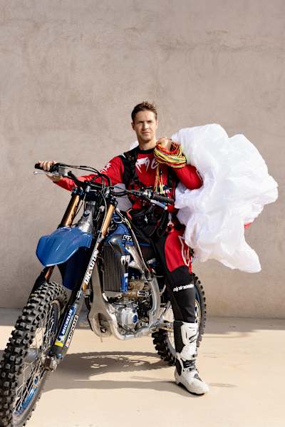 Portrait of Tom Pagès with his parachute and motorbike.