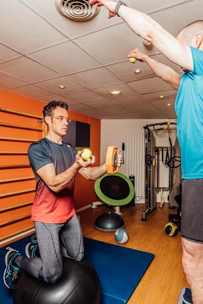 Thierry Neuville catches tennis balls while holding a weight and looking straight ahead.