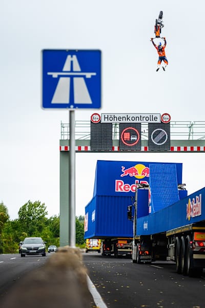 Luc Ackermann performt einen Tsunami Backflip über eine Höhenkontrolle auf einer Autobahn. Die Autos im Gegenverkehr fahren einfach weiter. 