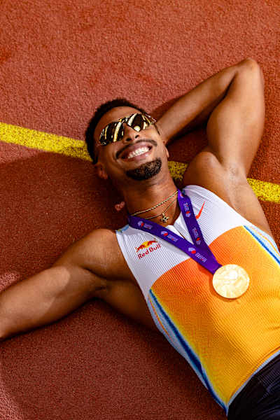 Leo Neugebauer lying on a track in Germany with his gold medal from the 2025 World Athletics Championships in Tokyo.