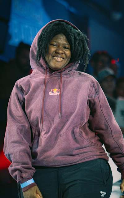 Marithea sonríe con una sudadera con capucha de Red Bull durante una actuación en 2026 en Bogotá, Colombia, con el público animado y el ambiente del recinto a sus espaldas
