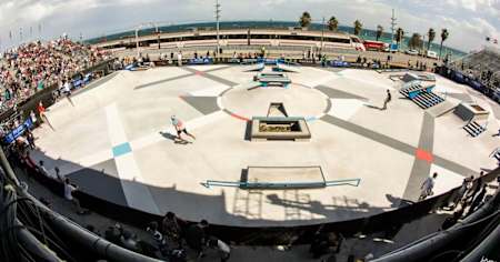 Fisheye image from above at the Skate Agora skate park in Barcelona. A train passes by in the background and the beach can be seen. 