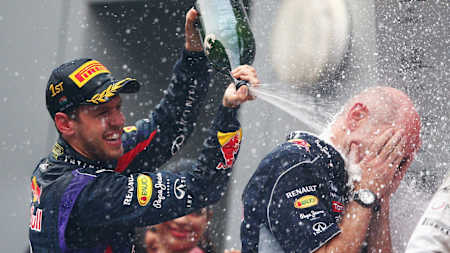 An image of Sebastian Vettel and Adrian Newey on the podium in India, celebrating with champagne.