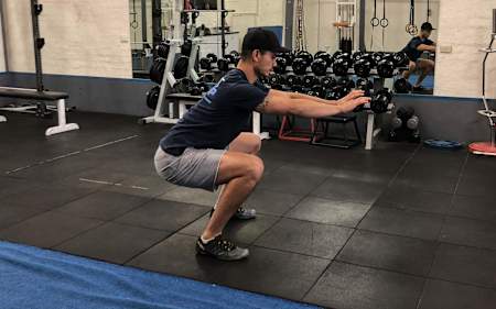 An athlete in the middle of a squat routine in the gym.
