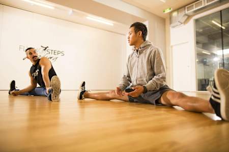 Dwóch mężczyzn rozciąga się na sali gimnastycznej