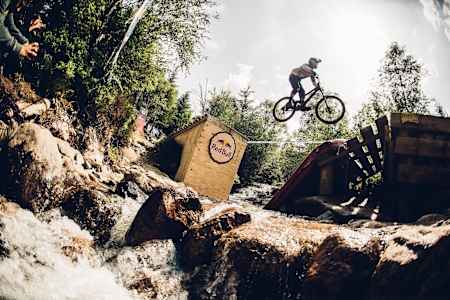 A competitor boosts over the river gap during qualifications at the Fort William World Cup on June 4, 2016