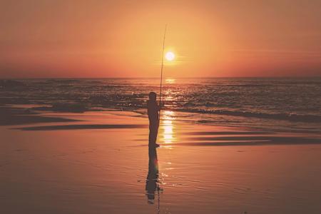 Imagen de un hombre pescando en la playa.