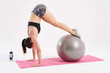 腹部收紧核心用力，将球往身体滚动并抬高臀部。