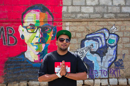 Rapper Gubbi poses for a photo besides a mural of Chester Bennington near Jyoti Nivas College