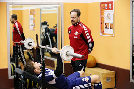 Trener osobisty udziela wskazówek ćwiczącemu na siłowni