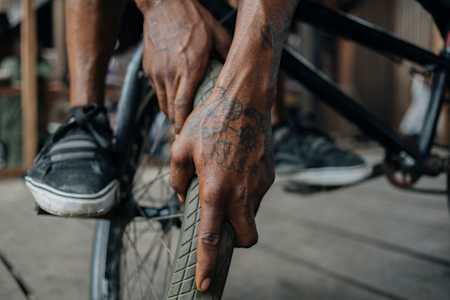 A BMX rider checks the tyres of their bike for air pressure and other issues in the wheel