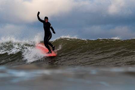 Jill Manos surfing winter waves In Lawrencetown, Nova Scotia, Canada on December 09, 2021